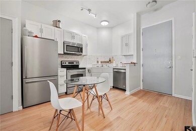 Kitchen featuring appliances with stainless steel finishes, light wood finished floors, backsplash, light countertops, and white cabinets