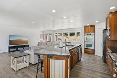 Kitchen featuring brown cabinets, wood finished floors, a kitchen breakfast bar, stainless steel appliances, and recessed lighting