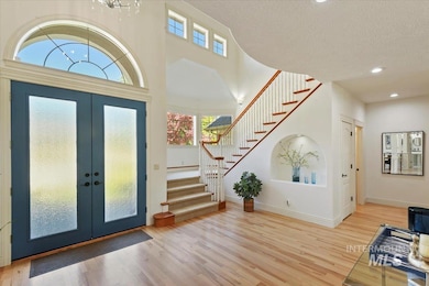 Entryway featuring french doors, stairway, wood finished floors, a high ceiling, and a textured ceiling