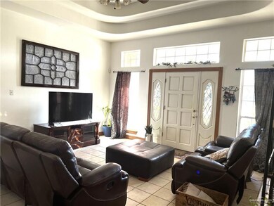 Living room featuring a raised ceiling, ceiling fan, and light tile patterned flooring