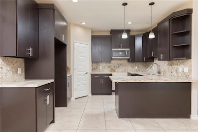 Kitchen featuring open shelves, light tile patterned floors, stainless steel microwave, tasteful backsplash, and recessed lighting