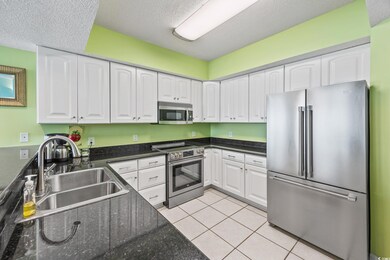 Kitchen featuring stainless steel appliances, a sink, white cabinets, and a textured ceiling
