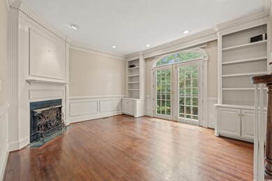 Unfurnished living room featuring built in shelves, light hardwood / wood-style floors, and crown molding