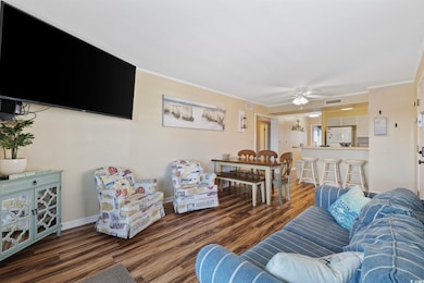 Living area featuring crown molding, dark wood-style flooring, and ceiling fan
