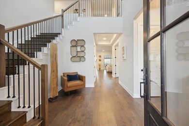 Foyer entrance featuring stairway, wood finished floors, baseboards, and a towering two story ceiling!