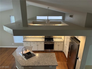 Kitchen featuring white cabinetry, high vaulted ceiling, appliances with stainless steel finishes, dark wood finished floors, and granite countertops