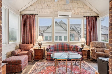 Sunroom featuring vaulted ceiling, a wall mounted AC, and stone finish floors