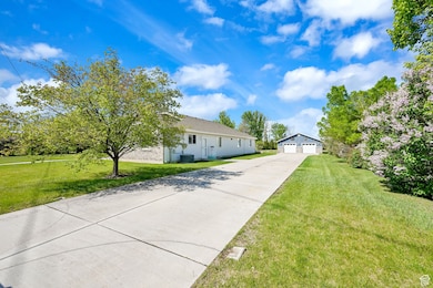 View of front of property featuring a garage, an outdoor structure, and a front lawn