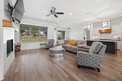 Living room with wood finished floors, ornamental molding, recessed lighting, ceiling fan, and a fireplace
