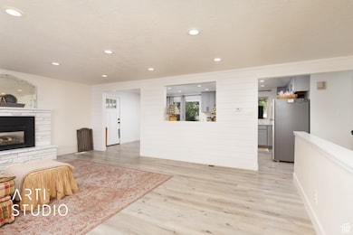 Living area with recessed lighting, light wood-style floors, a textured ceiling, a fireplace, and wooden walls