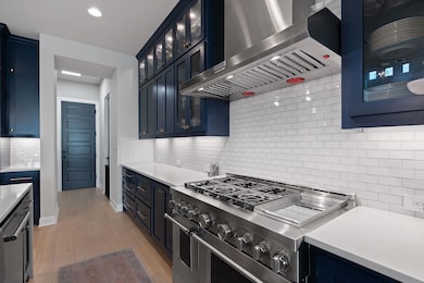 Kitchen with blue cabinetry, double oven range, a