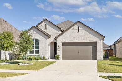 French country inspired facade featuring brick siding, a front lawn, concrete driveway, and a garage