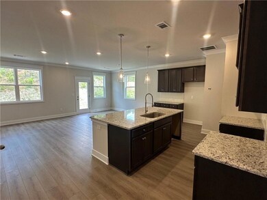 Kitchen featuring a sink, ornamental molding, baseboards, dark wood finished floors, and a kitchen island with sink