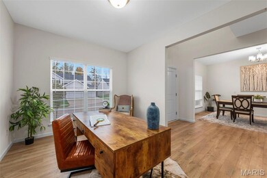 Home office featuring light wood-style flooring, healthy amount of natural light, and a chandelier