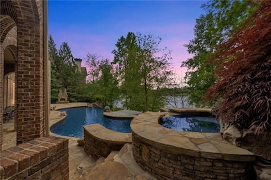 Pool at dusk with an in ground hot tub and a patio