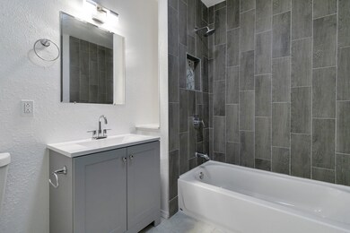 Modern bathroom with gray tiles, white tub, vanity
