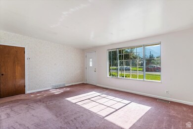 Carpeted spare room with baseboards and wallpapered walls
