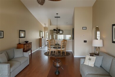 Living room with wood finished floors, high vaulted ceiling, and a chandelier