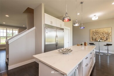 Second view of large kitchen,large refridgerator,large eat in Island and under mount microwave with views into formal dining room and entrance.  Sool the cool multi colored pendant lighting