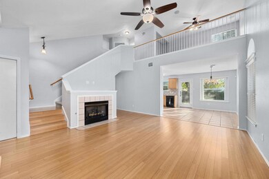 Unfurnished living room with a fireplace, high vaulted ceiling, a ceiling fan, light wood-type flooring, and stairway