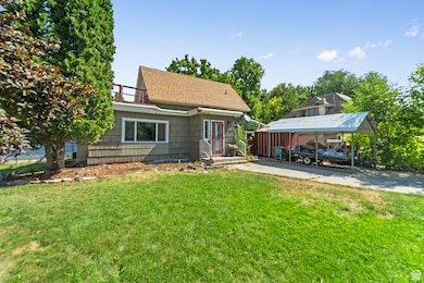 Front of house with a carport, a lawn, roof with shingles, and a balcony