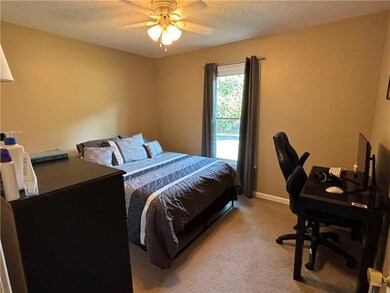 Bedroom featuring an office area, a textured ceiling, and light carpet