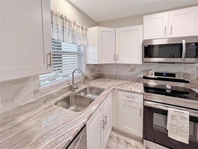 Beautifully updated Kitchen featuring white shaker, wood cabinets, granite countertop, stainless steel appliances and custom tiled backsplash.