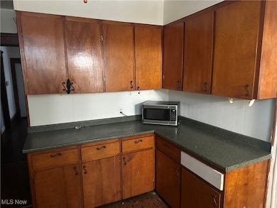 Kitchen with dark countertops, brown cabinets, and stainless steel microwave