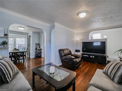 Hardwood floored living room with a textured ceiling and crown molding