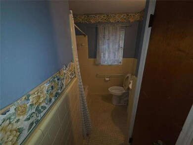Full bath with tile walls, a shower, toilet, wainscoting, and tile patterned flooring