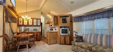 Kitchen with brown cabinetry, a chandelier, decorative light fixtures, light carpet, and freestanding refrigerator