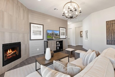 Living room featuring a tiled fireplace, wood finished floors, and a chandelier