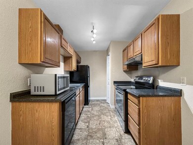 Kitchen with dishwasher, electric range, light tile floors.