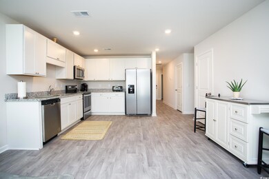 Kitchen with light hardwood / wood-style flooring, appliances with stainless steel finishes, sink, and white cabinets