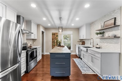 Kitchen featuring tasteful backsplash, appliances with stainless steel finishes, white cabinets, hanging light fixtures, and recessed lighting