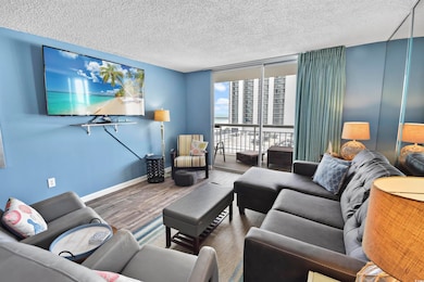 Living area with a textured ceiling, a wall of win