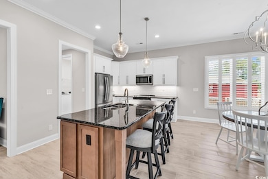 Kitchen featuring stainless steel appliances, a sink, crown molding, baseboards, and backsplash
