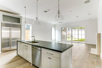 This light & airy kitchen is perfect for preparing meals using the impressive island with sink and stunning quartzite counters. This view showcases how the kitchen seamlessly opens to the family room for easy flow for entertaining.