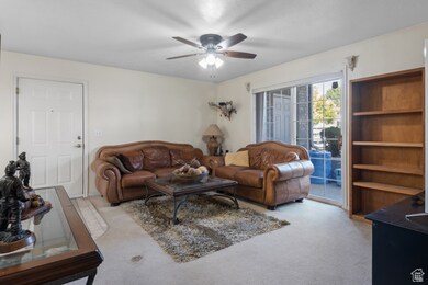 Carpeted living room featuring a ceiling fan