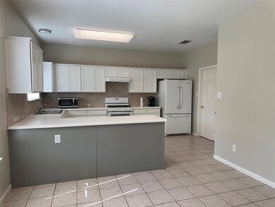 Kitchen with white appliances, a peninsula, light