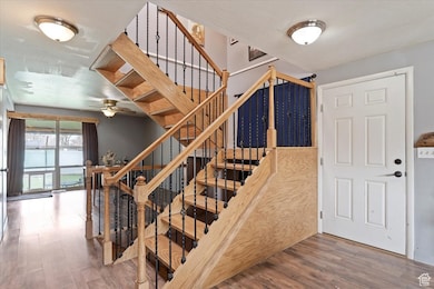 Stairs featuring wood finished floors and a ceiling fan