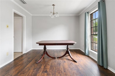 Dining room with a chandelier, wood finished floors, ornamental molding, and baseboards