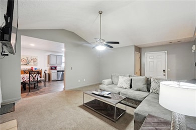 Living room featuring ceiling fan, a textured ceiling, lofted ceiling, and dark carpet