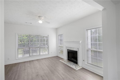Unfurnished living room with wood finished floors, ceiling fan, a textured ceiling, and a high end fireplace