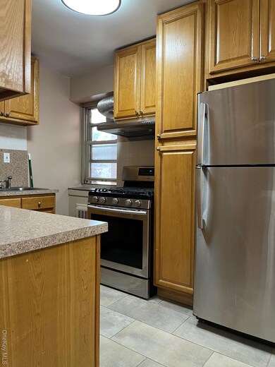 Kitchen with refrigerator, stainless steel range with gas cooktop, brown cabinets, and backsplash