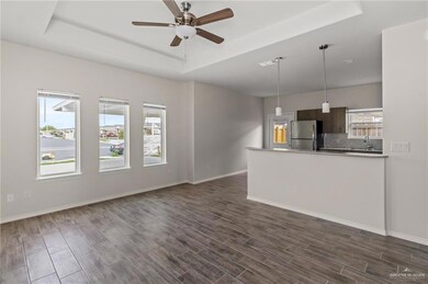 Unfurnished living room with dark hardwood / wood-style floors, a tray ceiling, sink, and ceiling fan