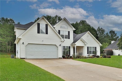 Traditional-style home featuring a front yard, driveway, and a garage