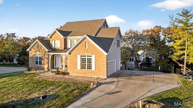 Traditional home with a shingled roof, a garage, concrete driveway, and brick siding