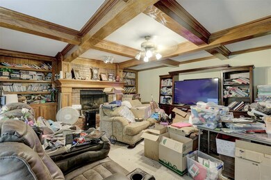 Carpeted living room featuring beam ceiling, built