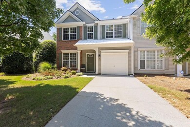 Traditional-style home featuring concrete driveway, a garage, a front lawn, and brick siding
